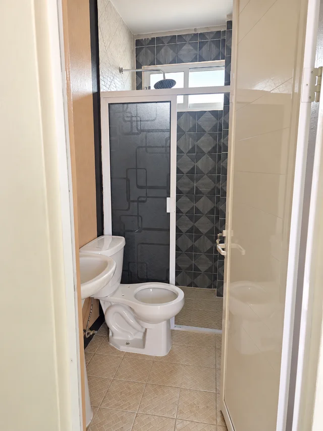 Baño de tonos claros del departamento doble de LUMA con lavabo, inodoro y cancel de ducha