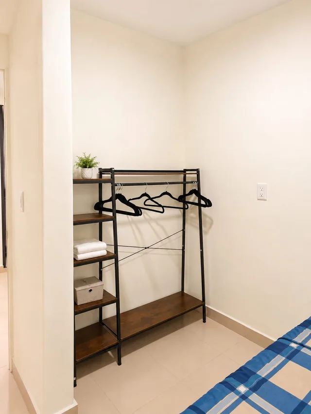 Vista del interior de LUMA con perchero, estantes y parte de la cama